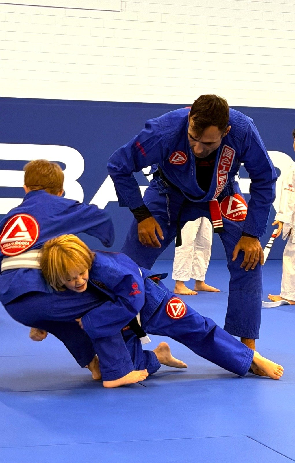 Instructor closely watching a child perform a Brazilian Jiu-Jitsu technique at Gracie Barra Artarmon