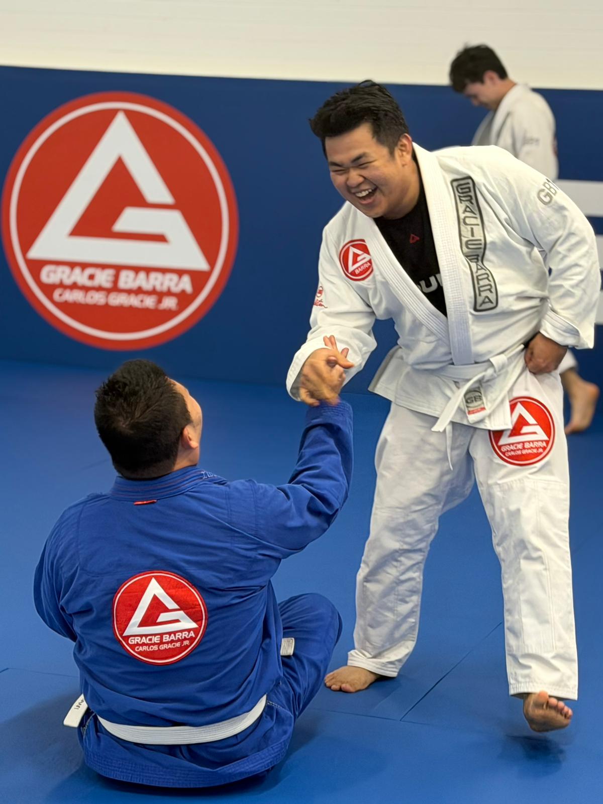 Adults smiling and showing respect during BJJ training at Gracie Barra Artarmon