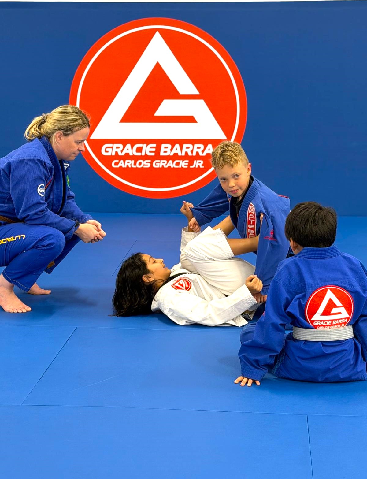 Coach helping kids learn Brazilian Jiu-Jitsu techniques at Gracie Barra Artarmon