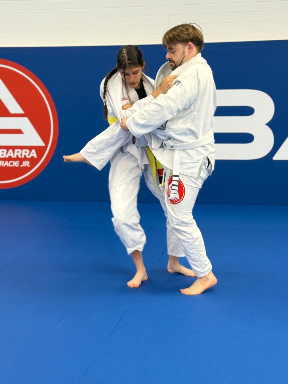 Male and female students practicing a Brazilian Jiu-Jitsu takedown at Gracie Barra Artarmon