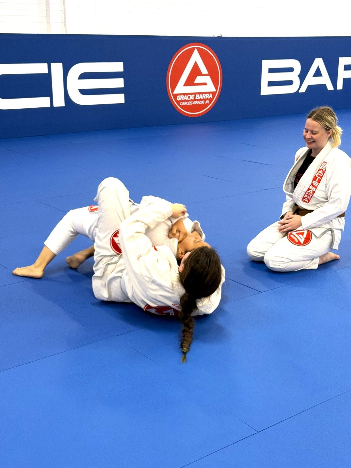 Female Brazilian Jiu-Jitsu coach helping two female students at Gracie Barra Artarmon