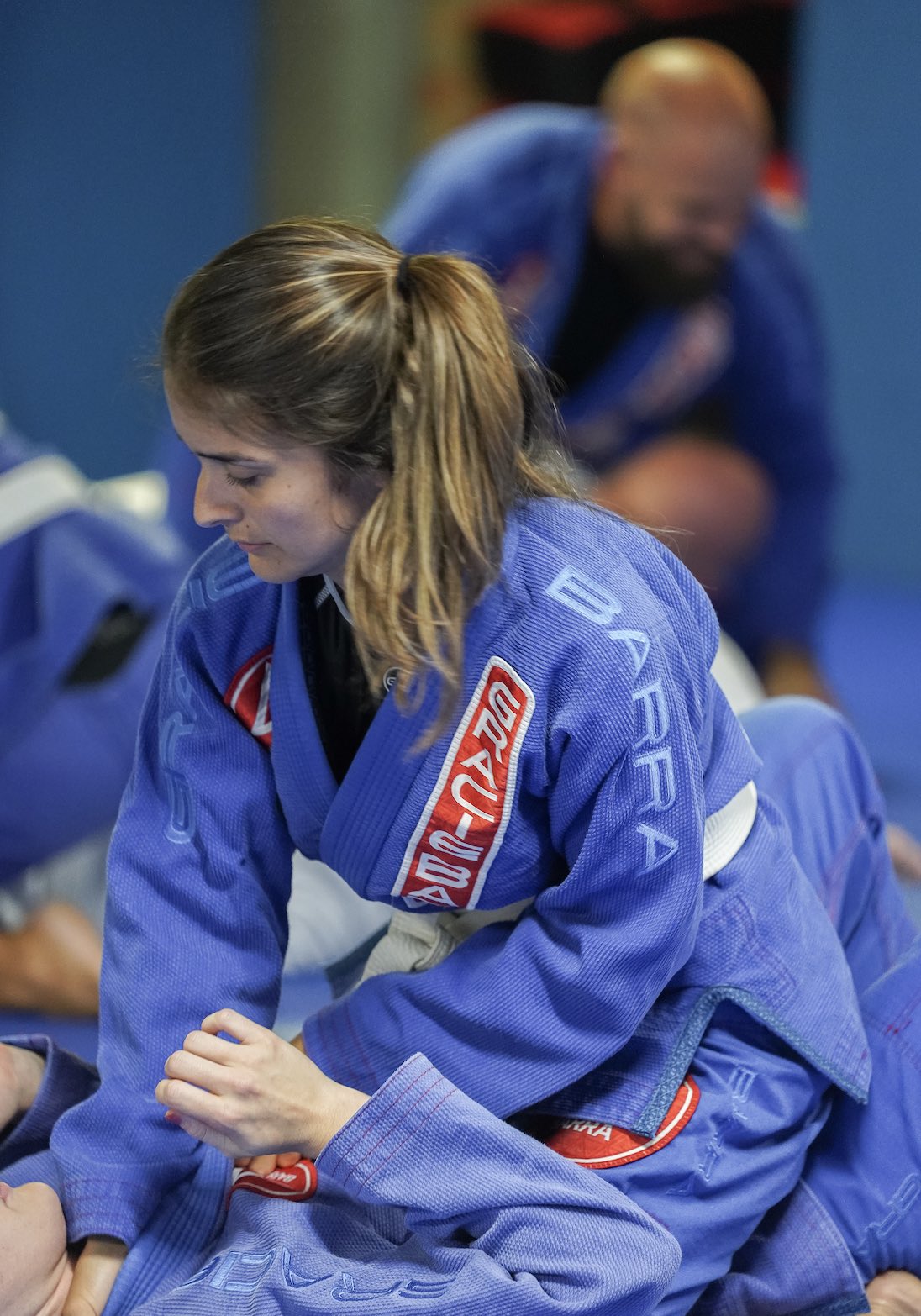 Beginner BJJ student in blue gi practicing mount position.