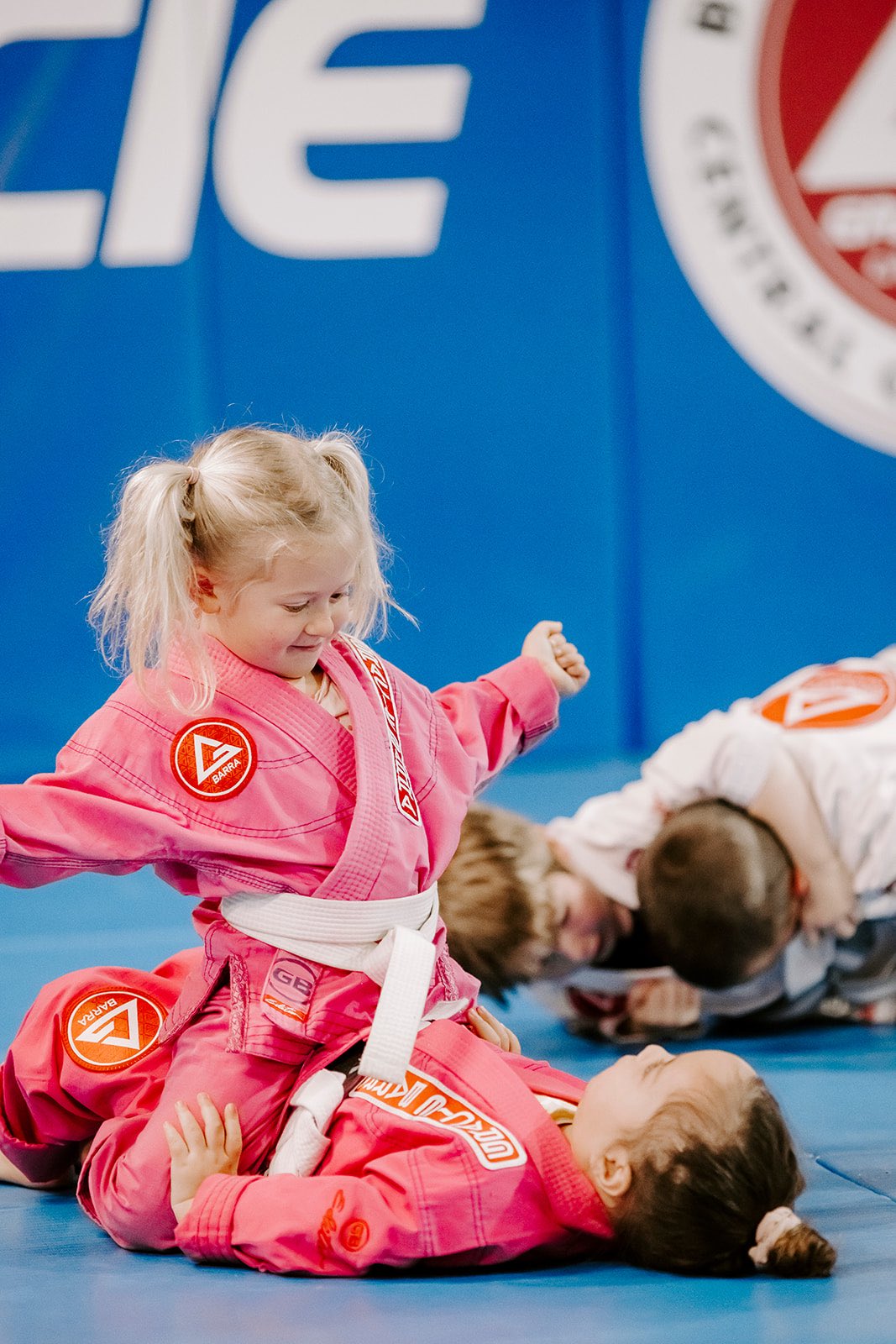 A happy 4-year-old girl wearing a pink gi practicing on the mat during our Little Champion 1 class at GB Central Coast in Erina, showcasing confidence, focus, and fun in a safe, supportive environment