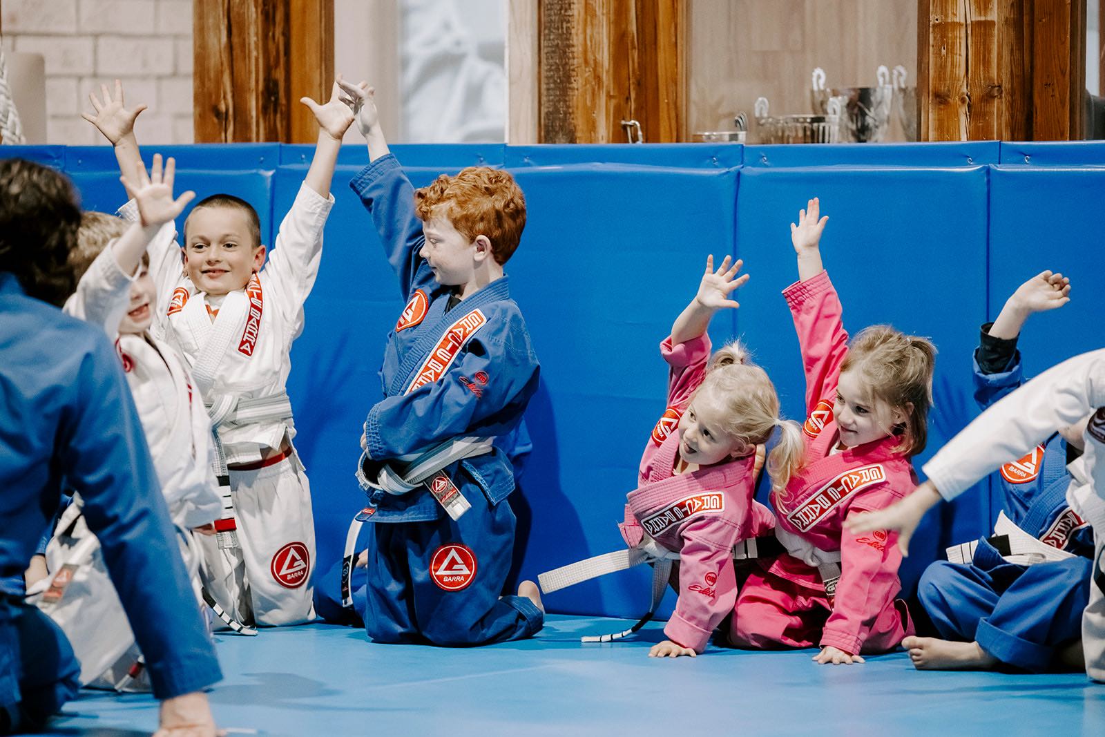 Four kids raising their hands and having fun during a BJJ kids’ class in Erina