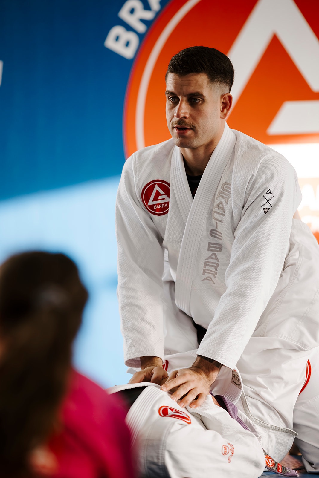 Black belt BJJ professor demonstrating a technique to students in class.