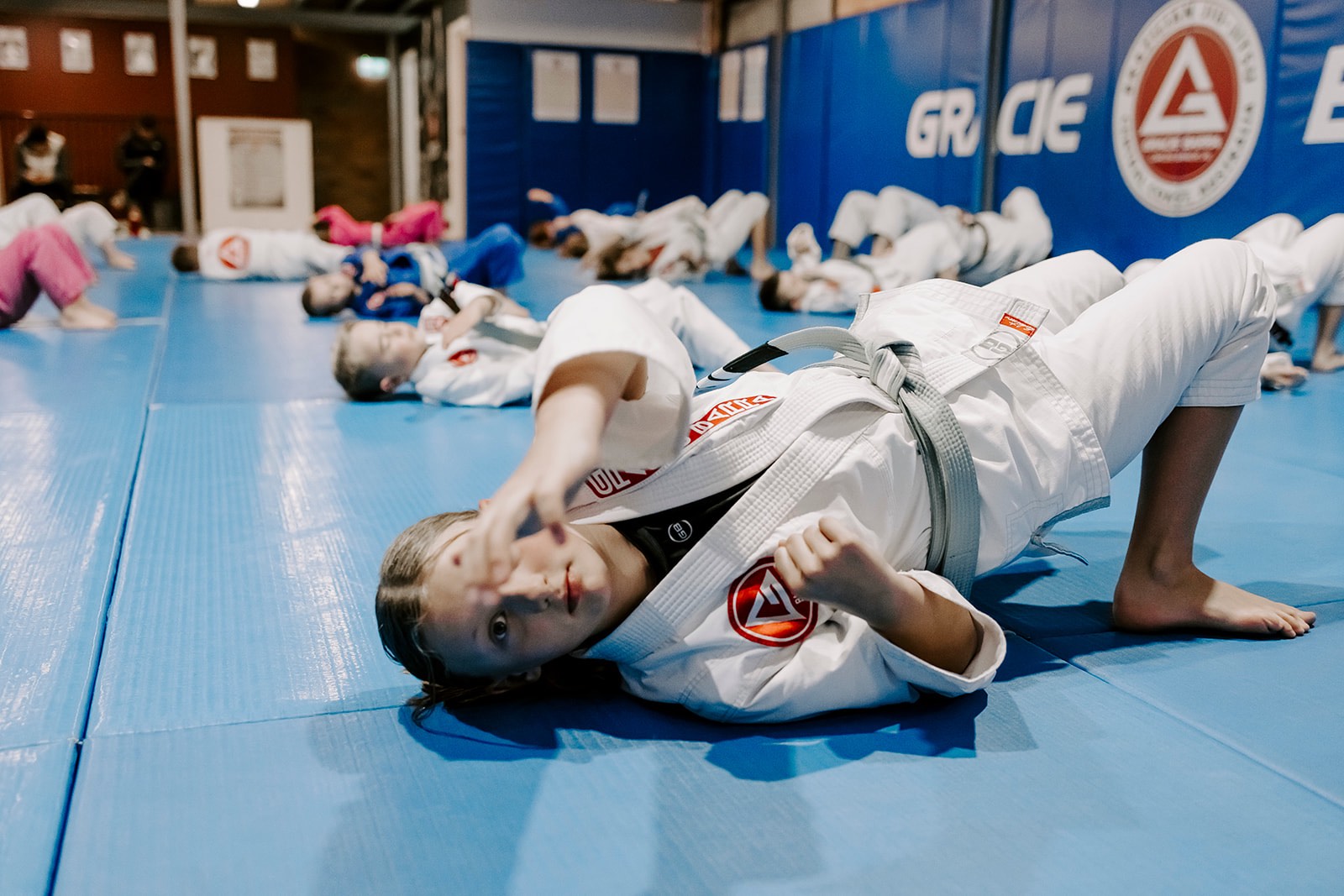 Junior BJJ students performing bridges during kids’ warm-up.