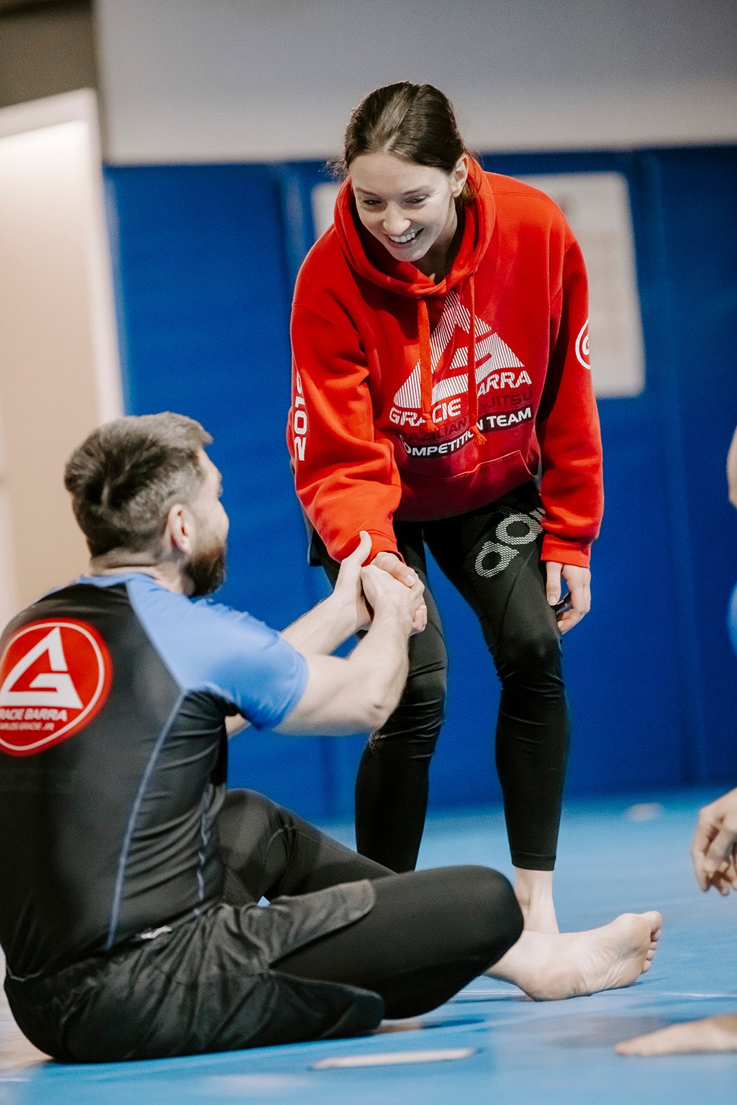 Two BJJ students smiling and greeting each other before class.